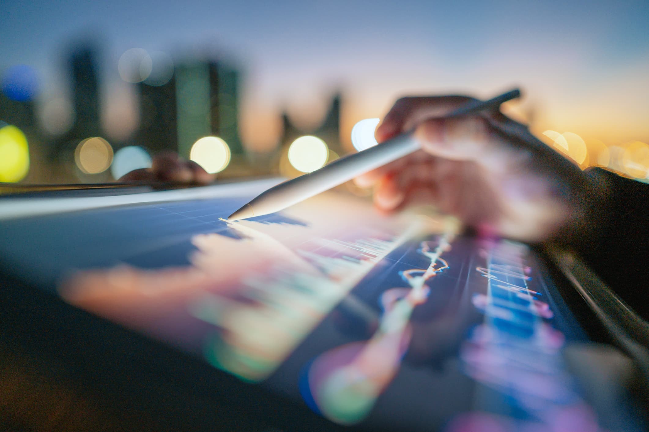 User with a Tablet and a Stylus Outside in Front of Cityscape